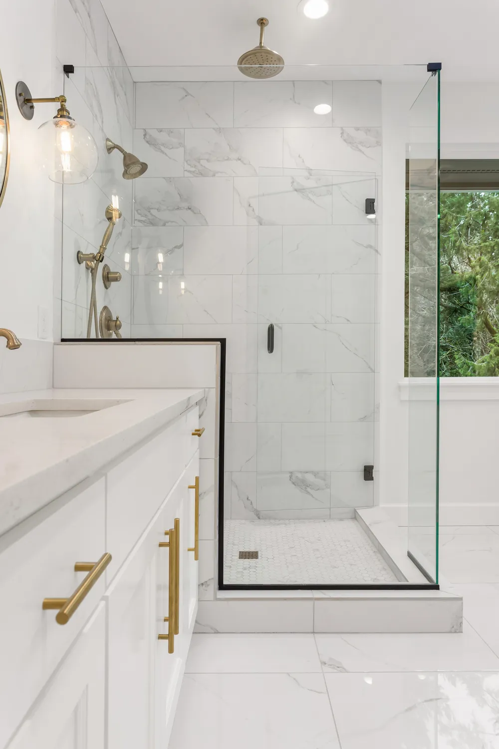Custom shower doors Chicago example: glass enclosure set on a tiled knee wall with thin black trim and brass fixtures