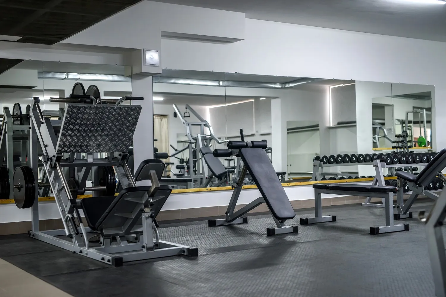 Industrial mirrors Chicago example: a long wall of large mirror panels behind weight benches in a commercial gym